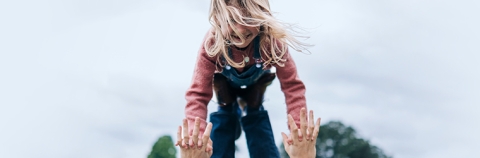 man tosses daughter up in the air