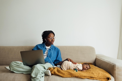 Mother working on laptop next to baby